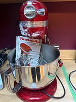 Front view of red KitchenAid bowl-lift stand mixer with stainless steel bowl and components inside.