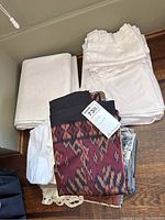 Various tablecloths and linen napkins stacked together with visible different textures and patterns.