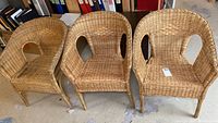 Wide shot of all three wicker chairs placed side by side on a concrete floor with shelving and office supplies in the background.