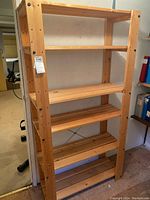 Full view of natural finish wooden 5-tier utility shelf showing front and side with shelves empty.
