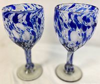 Pair of blue and white hand blown glass goblets with dot and swirl patterns shown side by side.