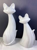 Front view of two ceramic cats, one taller and one shorter, showing marble veined finish and smooth texture.