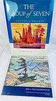 Two hardcover books stacked vertically: "The Group of Seven Art for a Nation" on top showing a vibrant landscape painting on cover, and "In the Footsteps of the Group of Seven" below with a painting of a tree and water on cover.