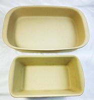 Top-down view of two rectangular beige stoneware baking dishes stacked, showing interiors and size difference.