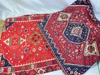 Two pillow cases, predominantly red with intricate floral and geometric designs, laying flat showing pattern details.