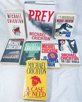 All 8 Michael Crichton novels arranged upright for viewing titles and condition.