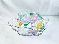 Angle view of Mikasa Savoir Vivre large crystal bowl showing embossed hibiscus flowers in purple, green, yellow, and pink accents with scalloped rim.