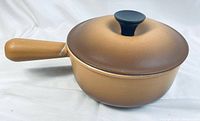 Brown enameled Le Creuset small saucepan with handle and matching lid shown from side angle.