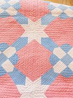 Close-up of quilt showing star-shaped white stitching and surrounding pink and blue fabric sections.