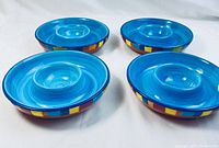 Four turquoise blue ceramic chip and dip bowls showing the interior and central dip area.