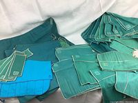 Group of approximately 30 various sized turquoise and teal fabric dust covers with white stitching and Birks logo, most sewn for cutlery storage and preservation of silverware.