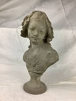 Front view of concrete bust on round pedestal against a white draped background