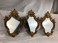 Three giltwood Rococo style mirrors arranged side by side on white backdrop