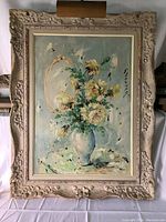 Full view of the floral oil painting with frame, showing yellow and white flowers in a blue vase against a muted background.
