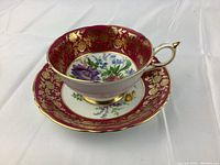 Teacup seated on saucer, angled front view showing interior floral motif and gilt border