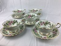 Five matching teacups and saucers arranged in a group