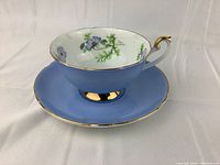 Side angle showing teacup on its saucer, highlighting blue exterior and gold trim.