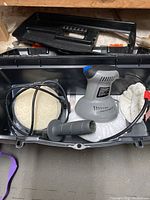 Electric 6-inch car buffer with attached polishing pad in black carrying case with extra polishing pads and detachable handle.