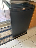 Black Danby Premiere mini fridge closed, showing black front with Premier logo.