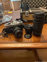 Vintage Fujica ST801 35mm camera body with attached lens, two additional lenses, and lens cap on wooden table.