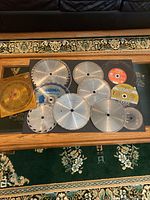 Top-down view of all blades and cutting wheels arranged on a glass-top table