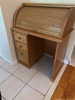 Front side view of the wooden roll top desk with closed roll top and 3 drawers on the left side.