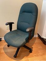 Front view of the green fabric rolling desk chair showing padded seat, armrests, and caster wheels base.