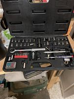 Open black plastic case showing a complete socket wrench set with ratchet, sockets, bits, and adapters organized in molds