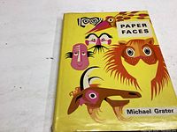 Front cover of the book showing the title 'Paper Faces' and author Michael Grater with eye-catching illustrated yellow jacket.