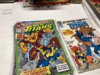 Photo of two Titans comic books laid flat showing detailed colorful covers with characters and storylines