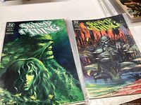 Photo of four Swamp Thing comic books with green and dark colored covers showing swamp creatures and characters