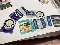 Photo showing nine Canadian-themed View-Master reels laid out on a white surface with various colorful labels including Banff and Ontario Vacationlands.