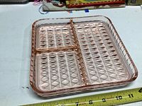 Top-down photo of a translucent pink depression glass serving tray with three divided sections and diamond pattern on bottom.