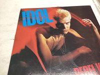 Front cover of Billy Idol Rebel Yell album showing artist with stylized red background.