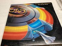 Front cover of the Electric Light Orchestra vinyl record album 'Out of the Blue'. Colorful artwork of a spaceship with the ELO logo.