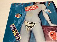 Front cover of the Rolling Stones 'Under Cover' vinyl album showing artwork with a blue figure and stickers.