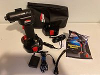 Front view of Air Hawk Pro cordless tire inflator with battery, charger, air hose, manual, and carrying case laid out on a flat surface.