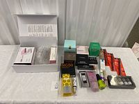 Full lot on table showing all boxed and loose products, including mini LED lamp and assorted cosmetics.