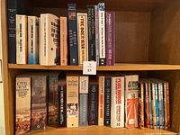 Bookshelves with assorted war history books by noted authors, showing titles and spines, displaying condition and quantity of books.