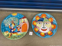 Two large 17-inch hand painted plates from Italy, shown front view on floor.