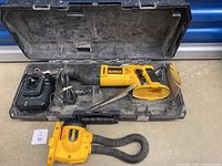 Top view of the reciprocating saw, charger, and flexible neck light in the hard case alongside the saw blades.