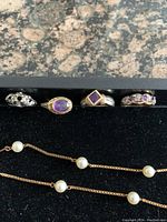 Frontal view of four rings aligned on black background with chain partially visible below