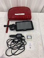 Front view of Garmin GPS with car mount, power cord, microSD card, and red carrying case