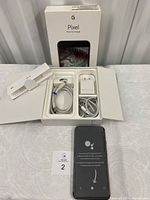 Open box showing phone, charger, cables, SIM tool and docs laid out