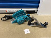 Makita electric power planer and Stanley hand planer side by side on concrete floor.