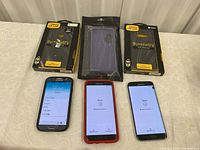 Three Samsung smartphones and three phone cases on a table