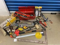 Photo of various handyman tools including saws, mallet, clamps, and measuring tools arranged on the ground