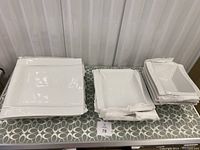 Wide shot showing the entire set of white porcelain dishes arranged in three neat stacks: dinner plates, side plates, and bowls.