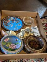 Overview of all five items in cardboard tray: two cloisonné bowls, cloisonné plate, alabaster bowl, foo dog figurine