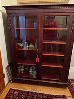 Front view of the bookcase showing glass doors and shelves with red felt liners